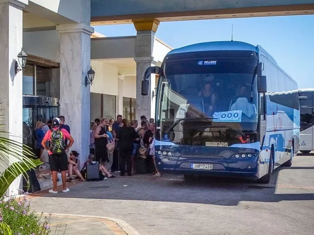 Evacuees wait to board buses as they leave their Rhodes hotel on Sunday