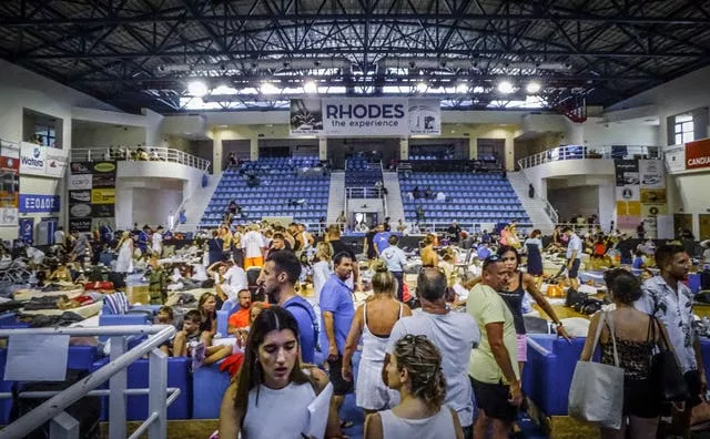Evacuees sit inside a stadium in Rhodes on Sunday