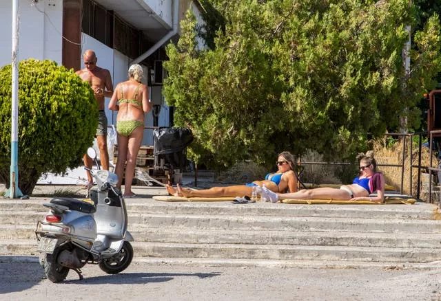 Tourists sunbathe outside a stadium where they are hosted following their evacuation