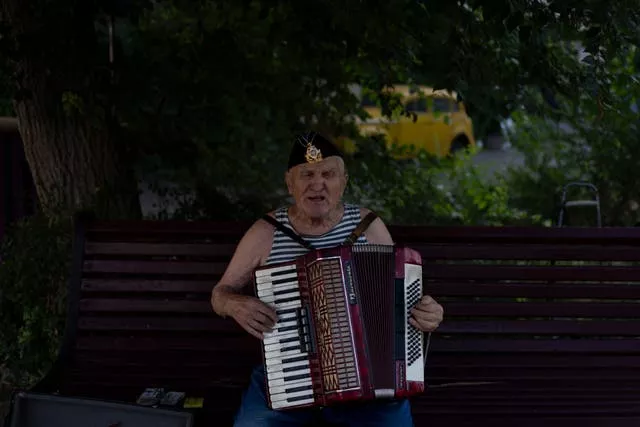 A street performer sings while playing the accordion at a popular beachside attraction in Odesa