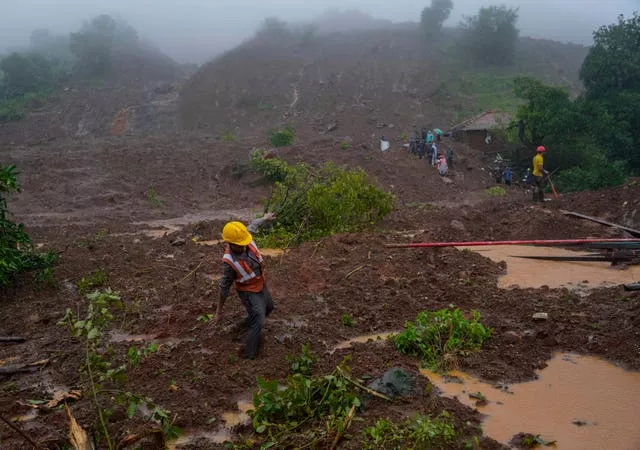 A rescue worker’s feet is stuck in mud at the site of a landslide (Rafiq Maqbool/AP)