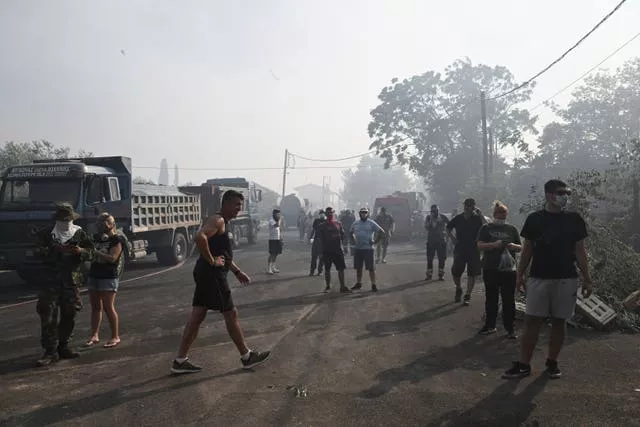 Residents stand on the road during a wildfire in the town of Nea Anchialos, near Volos city, central Greece, on Thursday
