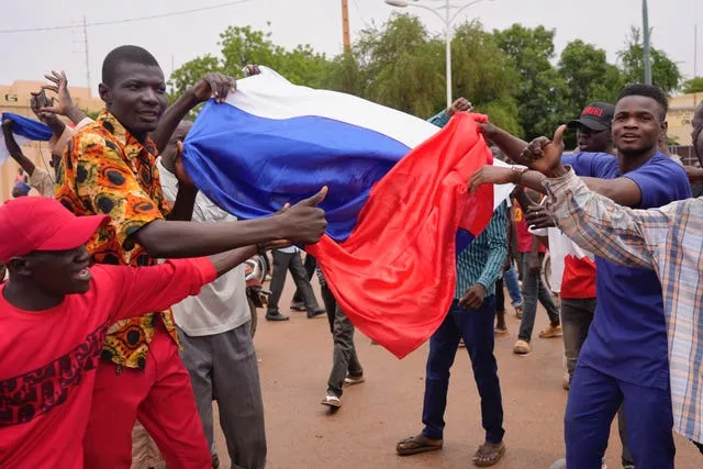 Supporters of mutinous soldiers hold a Russian flag as they demonstrate in Niamey, Niger