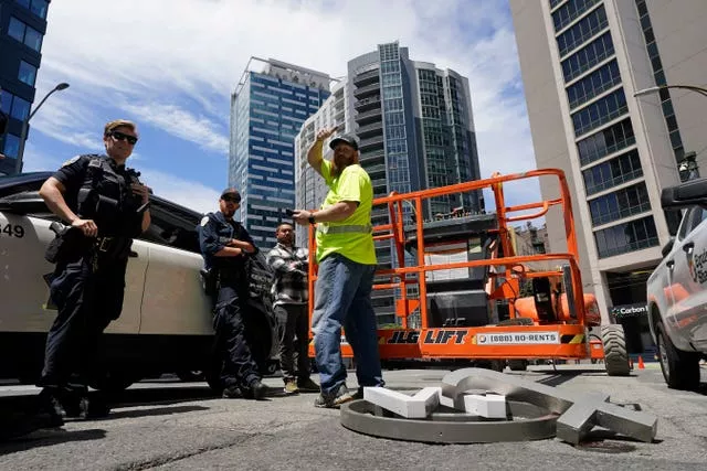 Police stop to talk with a workman after the removal of characters from a sign on the Twitter headquarters building was halted in San Francisco