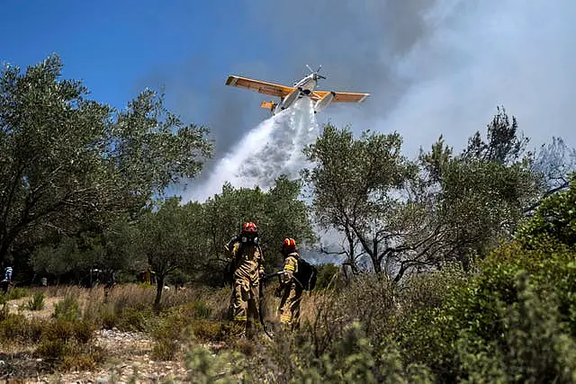 An aircraft drops water during a wildfire in the village of Vati, on the Aegean Sea island of Rhodes in Greece