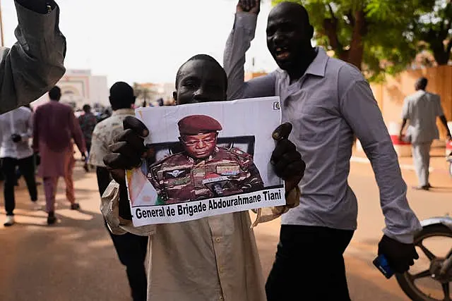 Nigeriens participate in a march called by supporters of coup leader Gen. Abdourahmane Tchiani, pictured