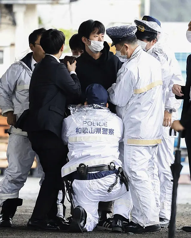 A man, centre, is detained after what appeared to be a smoke bomb was thrown at a port in Wakayama