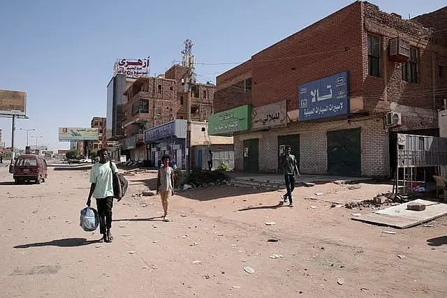 People walk past shuttered shops in Khartoum, Sudan 