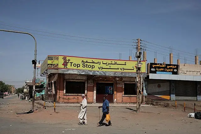 People walk past closed shops in Khartoum, Sudan