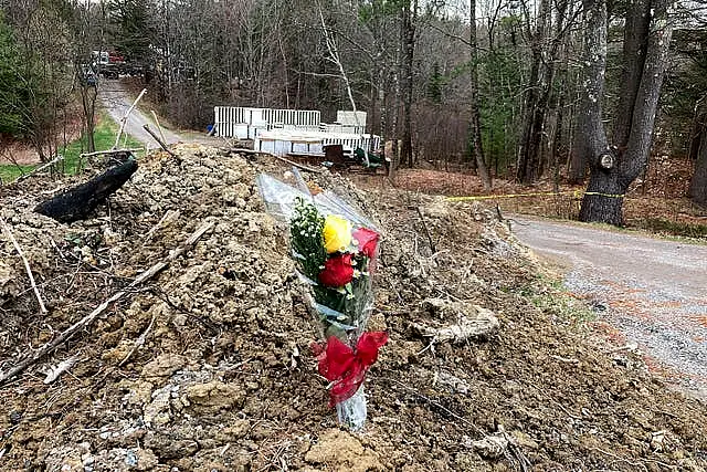 A lone bouquet of flowers marks a desolate makeshift memorial at the end of a driveway at a Bowdoin, Maine