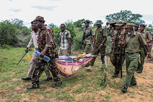 Police and local residents carry exhumed bodies in the village of Shakahola, near the coastal city of Malindi, in southern Kenya