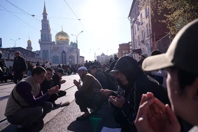 A group of men pray as other Muslims leave the area during Eid celebrations at the Moscow Cathedral Mosque