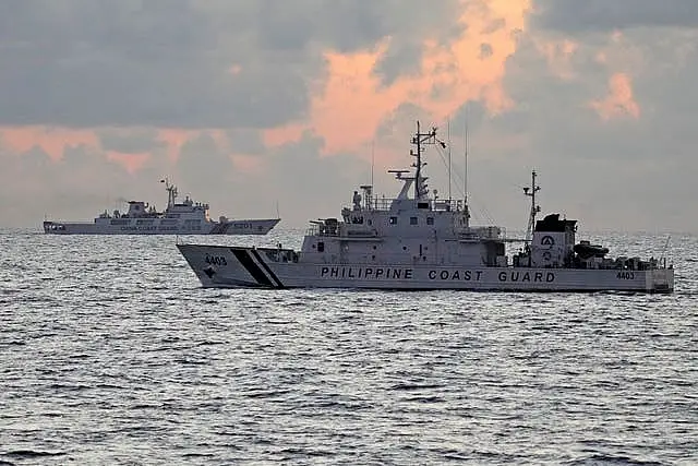 Philippine coastguard patrol vessel BRP Malapascua, right, passes by Chinese coastguard ship with bow number 5201 during sunrise near the Second Thomas Shoal