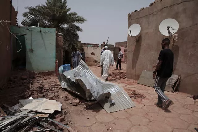 People walk by a house hit in recent fighting in Khartoum 