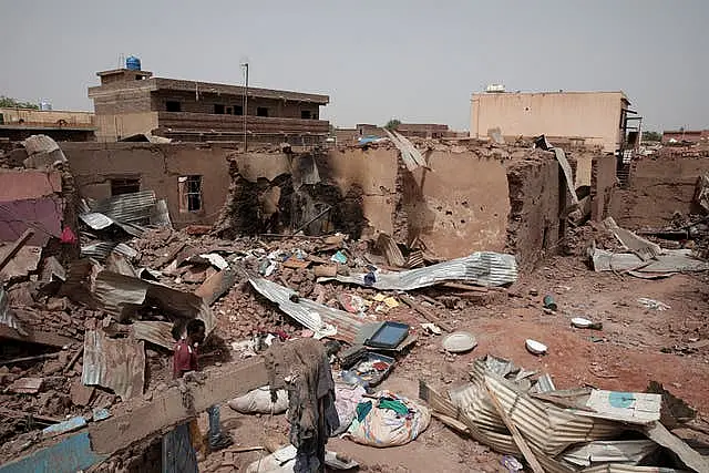 A man walks by a house hit in recent fighting in Khartoum, Sudan 