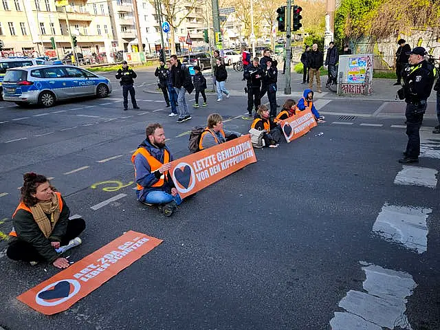 Climate activist Theodor Schnarr, second left, blocks a road with other activists during a climate protest in Berlin