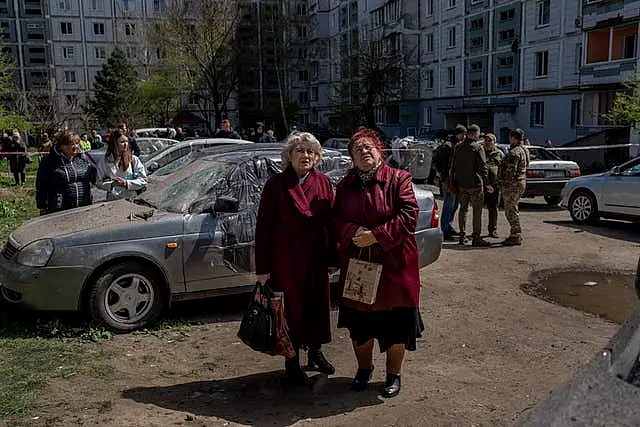 Residents watch the destruction of a residential building hit during a Russian attack in Uman