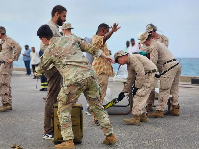 American nationals are searched by US soldiers before boarding a ship in Port Sudan