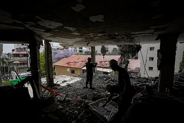 Israeli soldiers and municipality workers inspect the damage to an apartment building a day after it was hit by a rocket fired from the Gaza Strip, in Rehovot, Israel