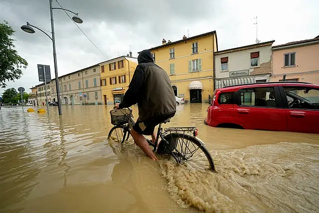 A cyclist rides through a flooded street in the village of Castel Bolognese