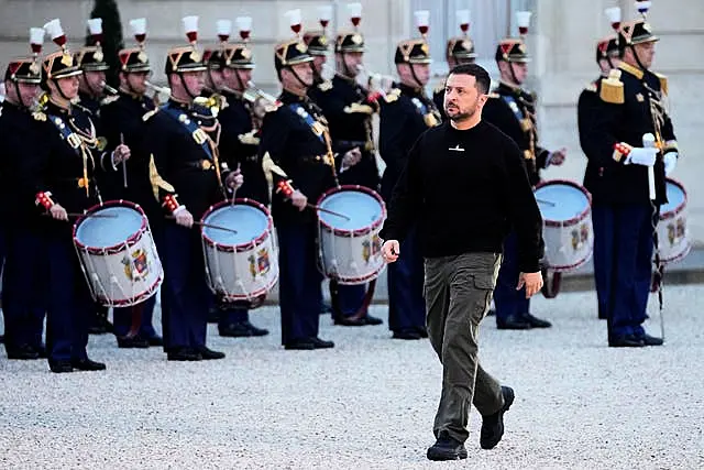 Ukrainian President Volodymyr Zelensky walks past Republican Guards as he arrives at the Elysee palace in Paris