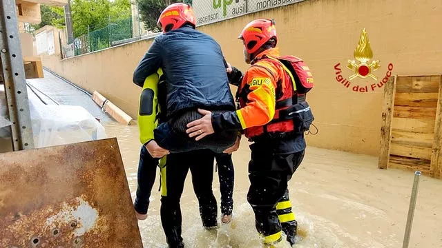 Firefighters rescuing a person from a flooded house in Riccione, in the northern Italian region of Emilia Romagna