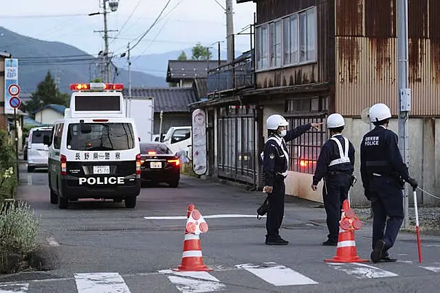 Police officers stand guard on a street leading to a building where a man was holed up in Nakano, central Japan