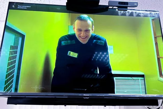 Russian opposition leader Alexei Navalny is seen on a TV screen, as he appears in a video link in a Moscow court in May 