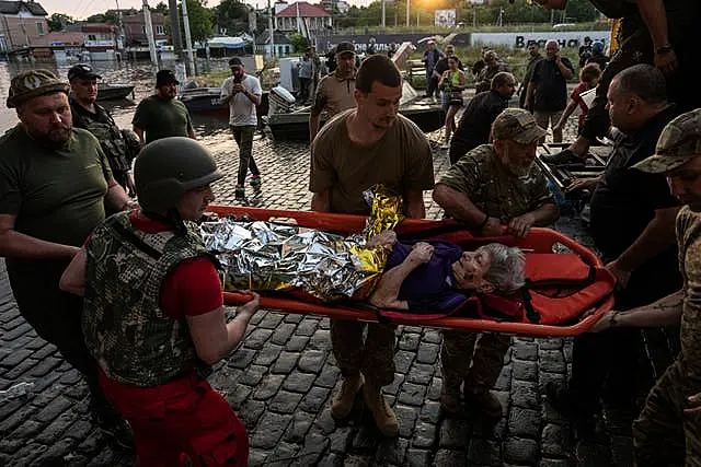 Volunteers evacuate a disabled elderly woman from a flooded neighbourhood in Kherson