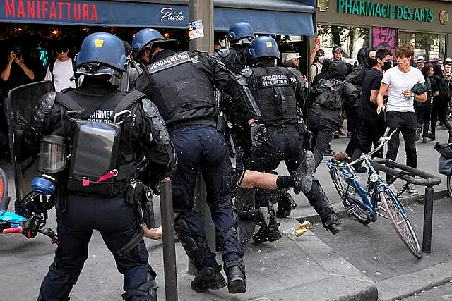 Riot police officers detain a person during a protest in Paris, France