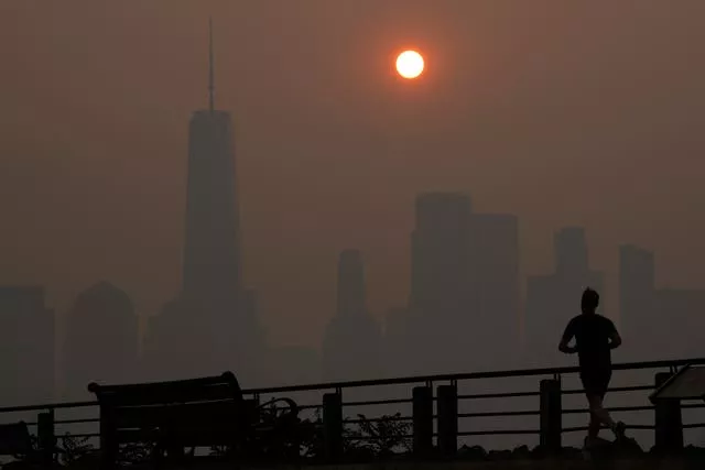 A man runs in front of the sun rising over the lower Manhattan skyline in Jersey City, New Jersey