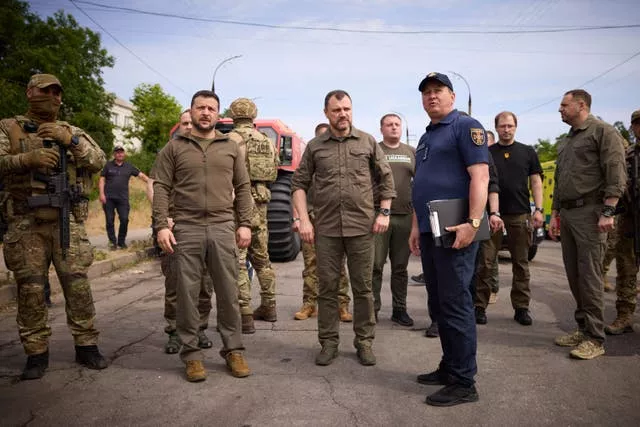 Ukrainian President Volodymyr Zelensky, left, visits the flood-hit areas in Kherson