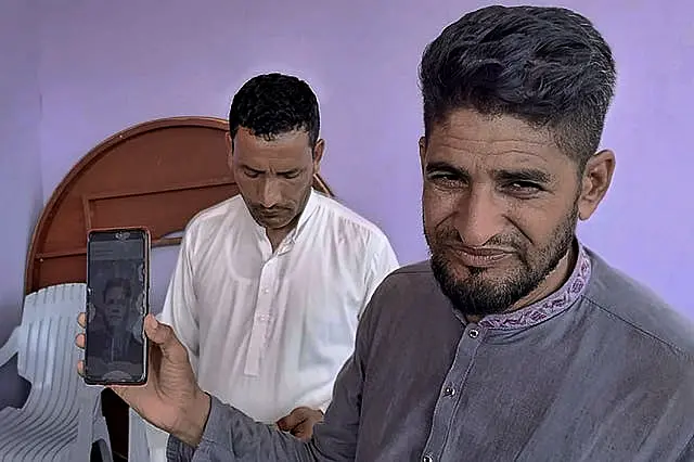 Raja Sakundar, right, holds a picture of his missing nephew on his phone