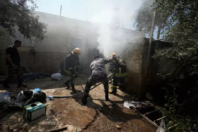 Palestinian firefighters try to extinguish a fire in a West Bank town
