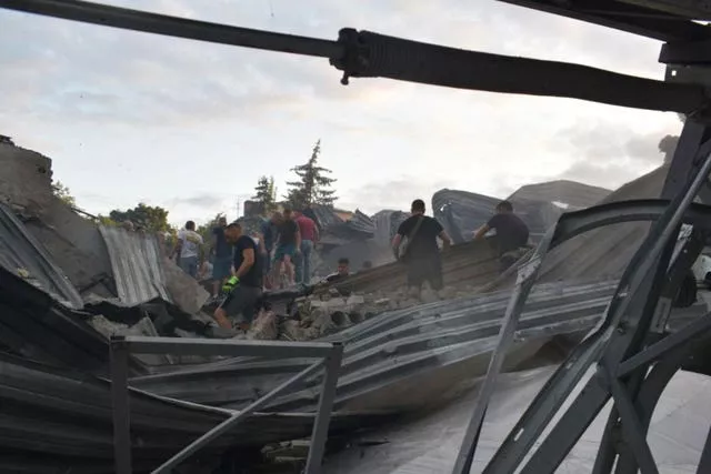 People clear the rubble on the roof of the restaurant destroyed by a missile
