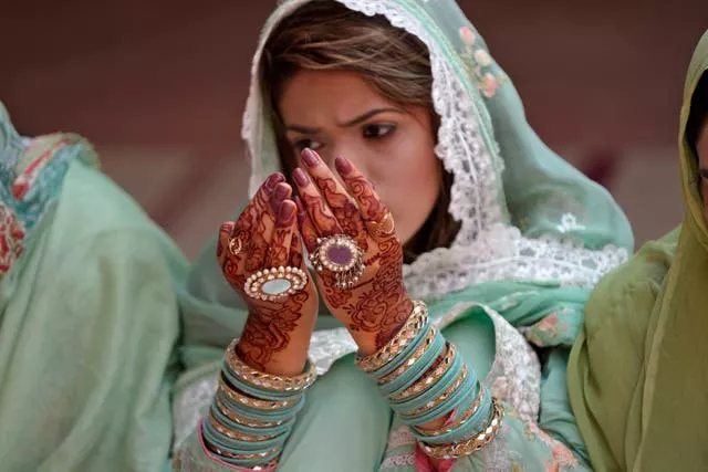 A woman has her hands painted with traditional henna as she attends Eid al-Adha prayers at historical Badshahi mosque in Lahore, Pakistan