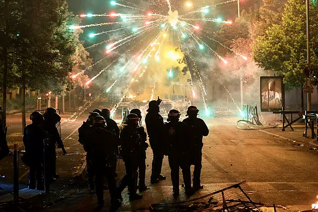 Police stand amid firecrackers on the third night of protests sparked by the fatal police shooting of a 17-year-old driver in the Paris suburb of Nanterre, France