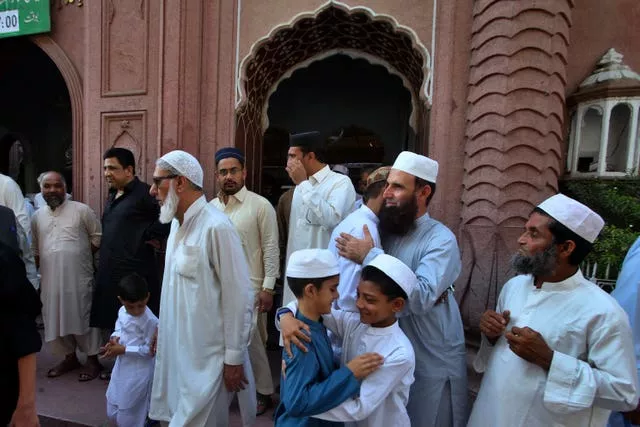 People greet each others after attending Eid prayers in Peshawar, Pakistan