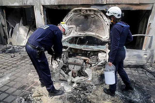 Police officers work on a charred car at the city hall of Mons-en-Barœul, northern France Thursday