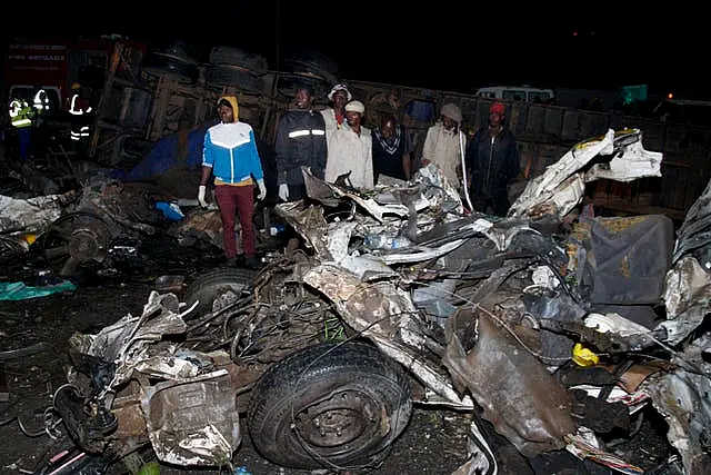 People stand near the wreckage