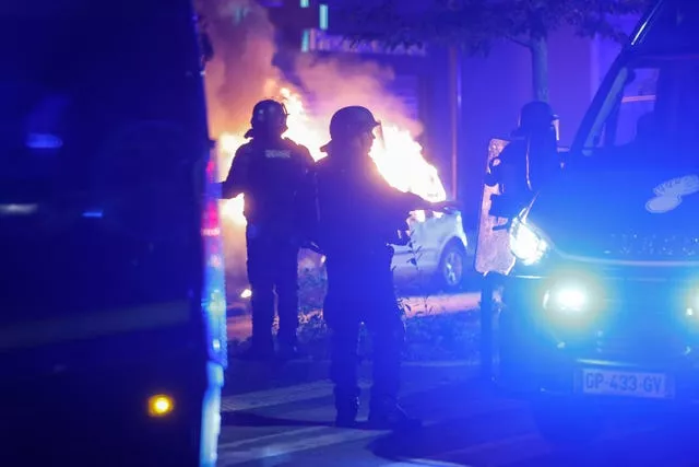 Riot police stand near a burning car in the La Meinau neighbourhood of Strasbourg