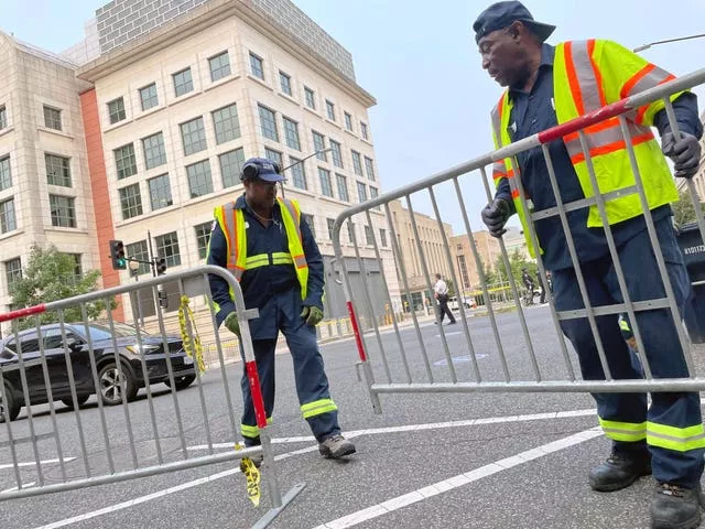 Workers put up barricades and secure the area outside the E. Barrett Prettyman U.S. Federal Courthouse