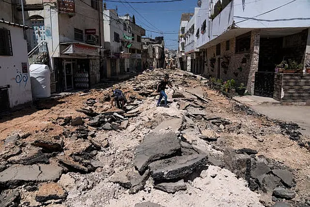 Two Palestinian school boys cross a damaged sreet 