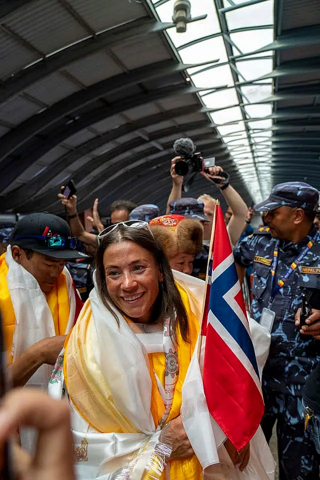 Norwegian woman mountain climber Kristin Harila, centre, who on Thursday set a new record by scaling the world’s 14 highest peaks in 92 days smiles as she and her Nepali Sherpa guide Tenjen Sherpa, arrive at the airport in Kathmandu, Nepal 