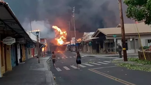 People watch as smoke and flames fill the air from raging wildfires on Front Street in Lahaina