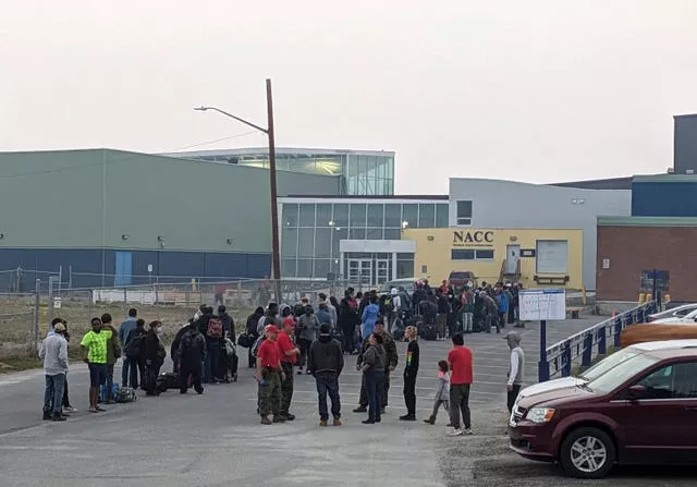 People without vehicles line up to register for a flight to Calgary, Alberta in Yellowknife