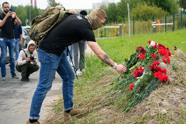 A man lays flowers at an informal memorial next to the former 'PMC Wagner Centre' in St Petersburg, Russia 