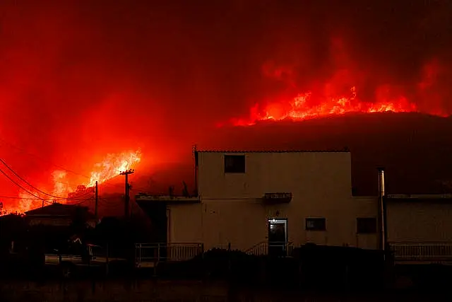 A wildfire burns a forest near a house in Avantas