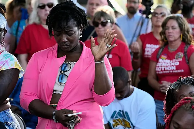 A woman attending a vigil for the victims of Saturday’s mass shooting bows her head in prayer