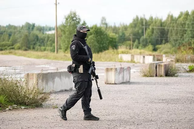 A Russian serviceman guards a road near a private jet crash near the village of Kuzhenkino, Tver region, Russia